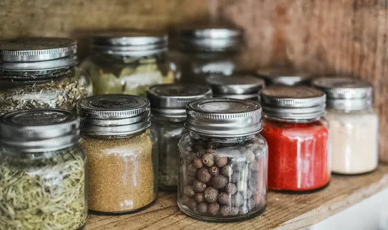Glass jars of seeds and spices on a wooden shelf